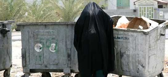 Bahraini woman looking through the trash in the mid-day heat